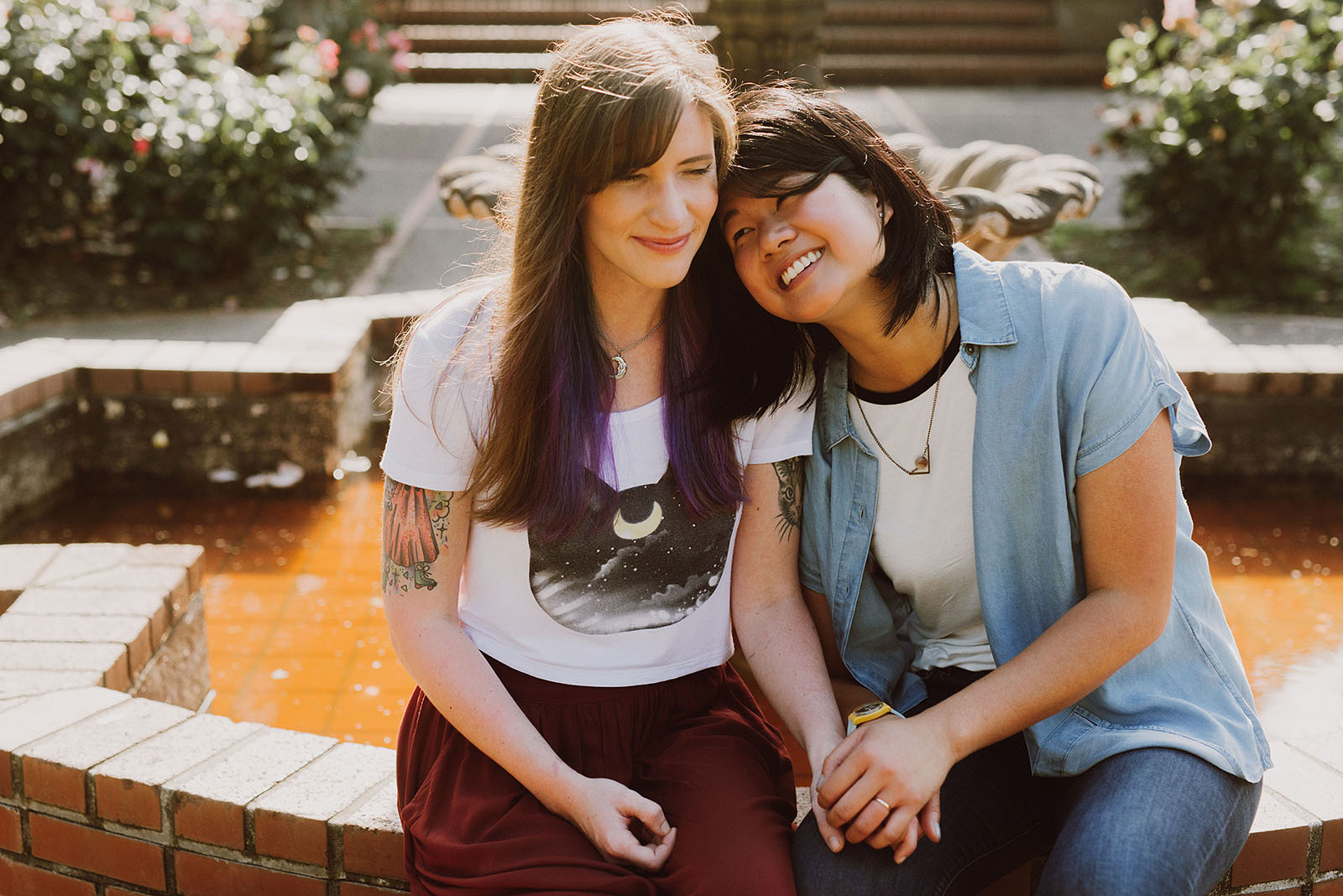 Newly engaged couple sitting down on a fountain - Portland Japanese Garden Proposal