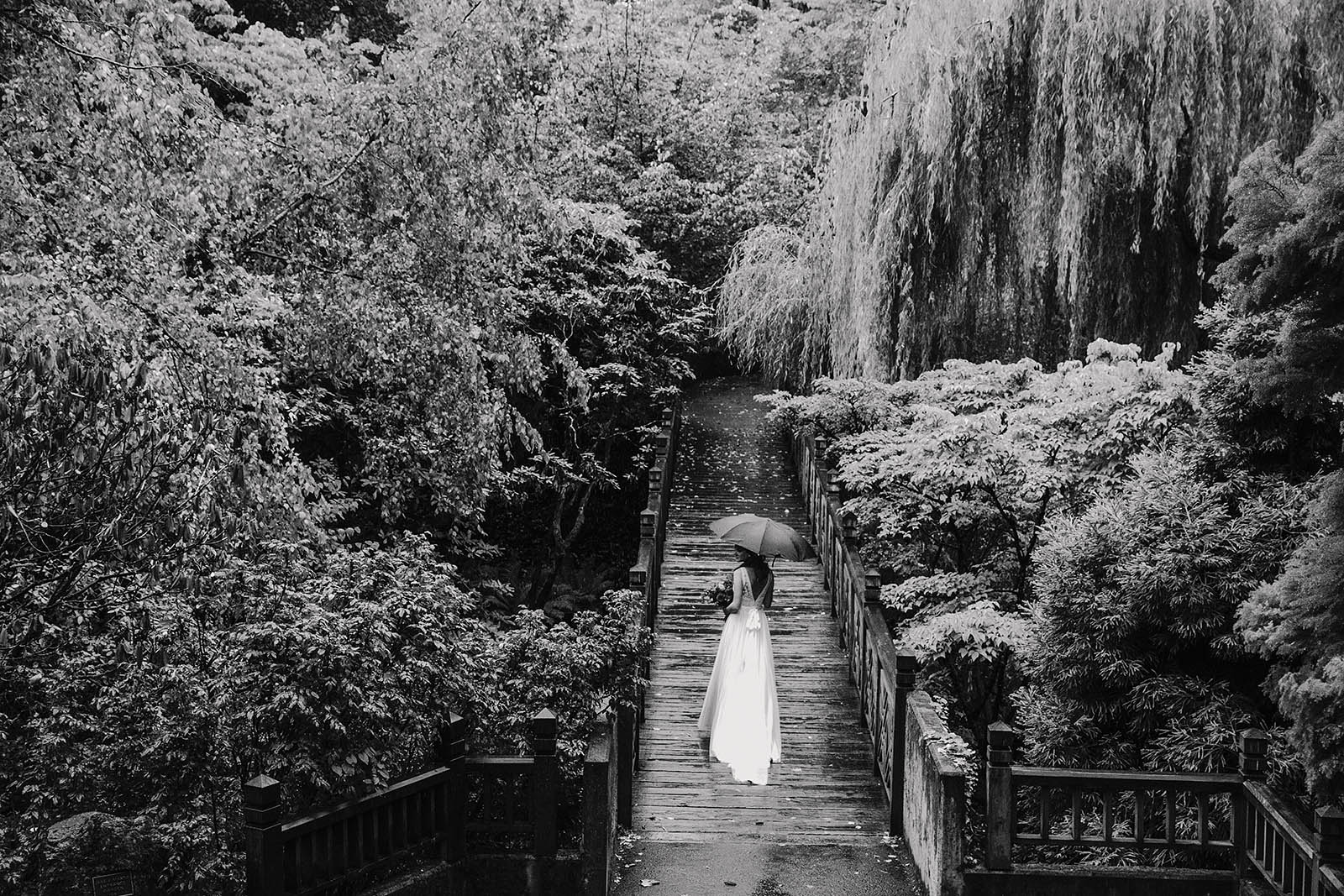 Bride posing on bridge before her Crystal Springs Rhododendron Garden wedding ceremony