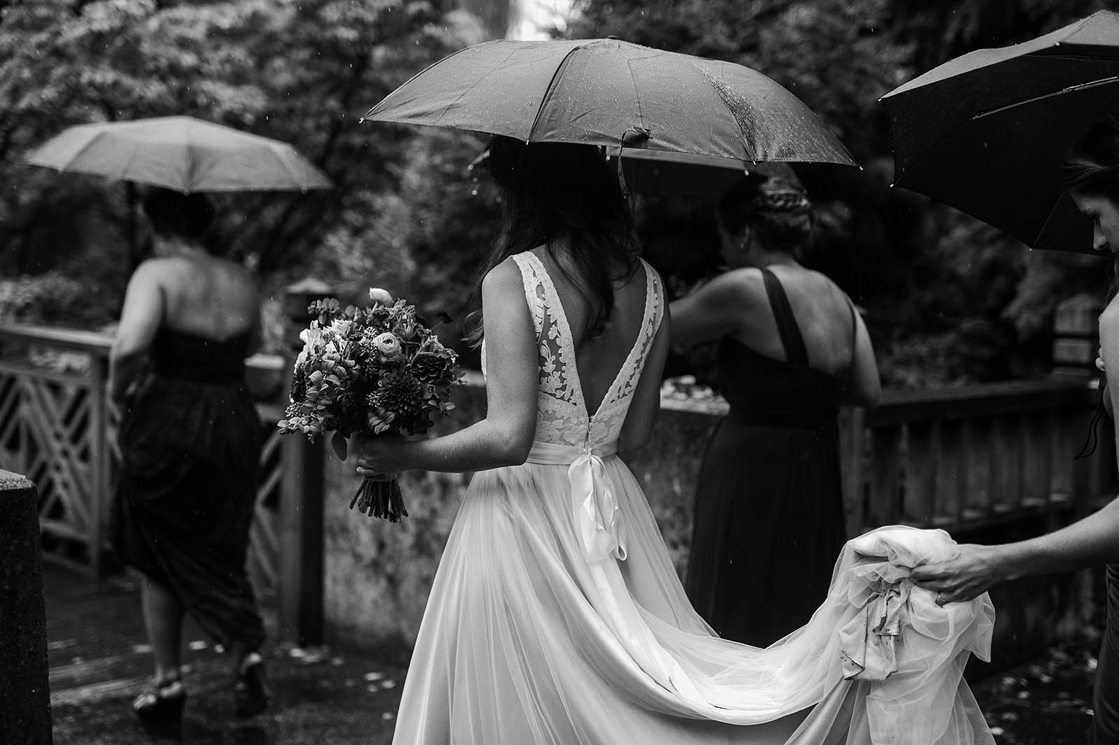 Mother of Bride holding dress during rainy ceremony at Crystal Springs Rhododendron Garden