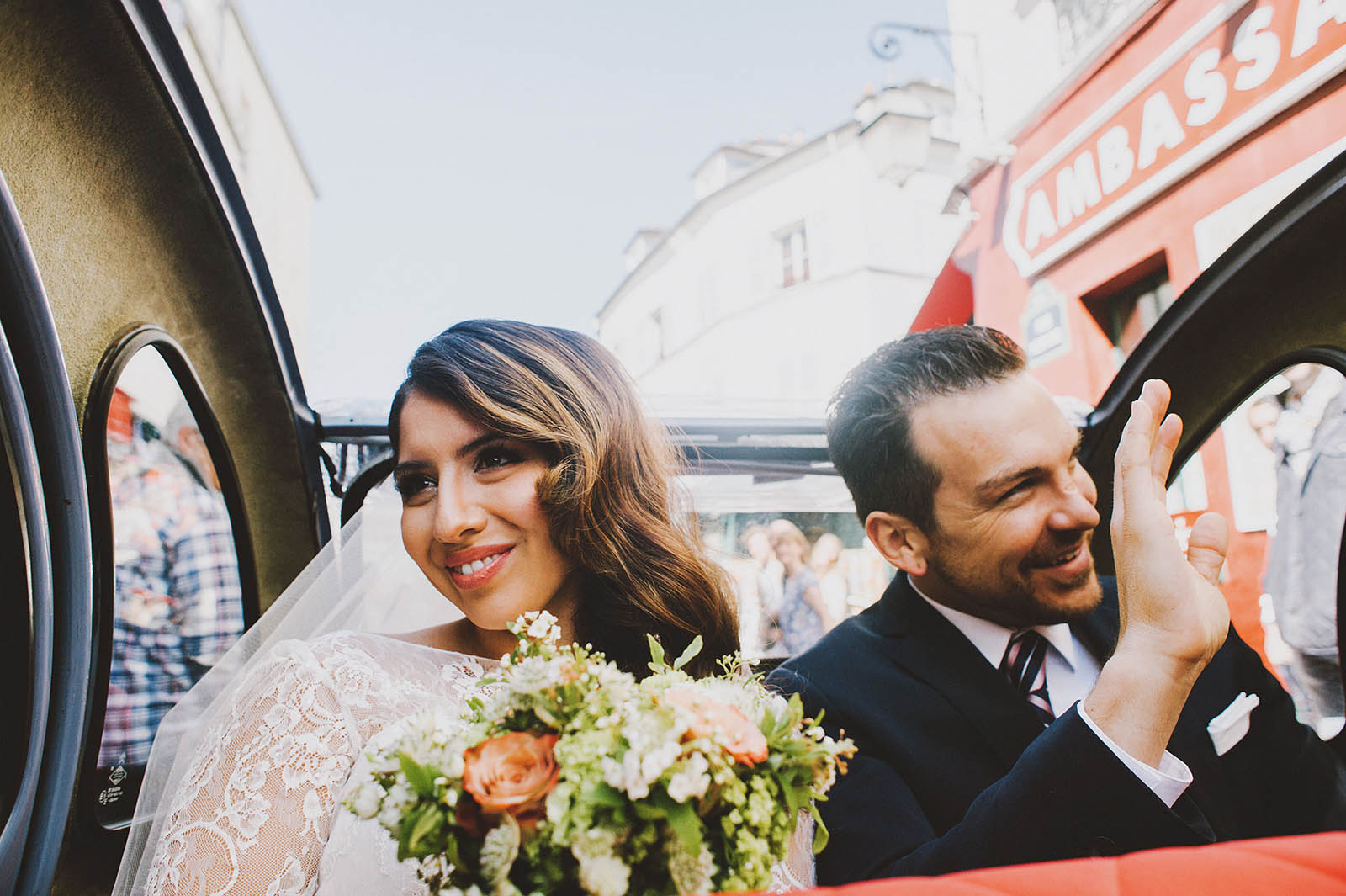 Bride and Groom waving at crowds of tourists in the street | Springtime Paris Elopement at Parc des Buttes Chaumont