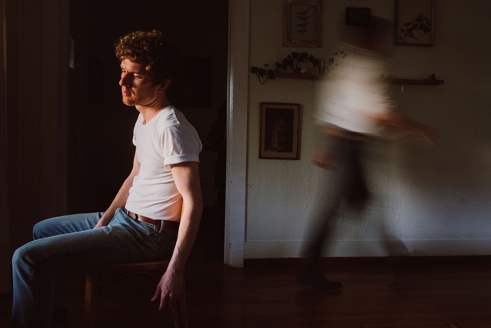 Lorain's lead singer looking out the window while a man walks behind him - Portland Music Photographer