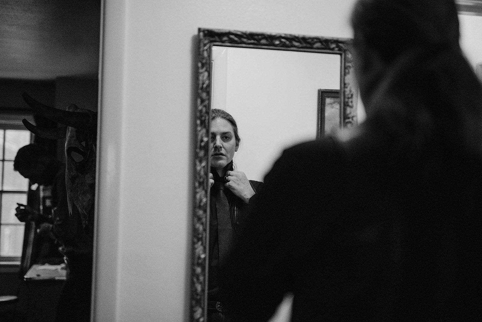 Groom looking in the mirror while tying a tie