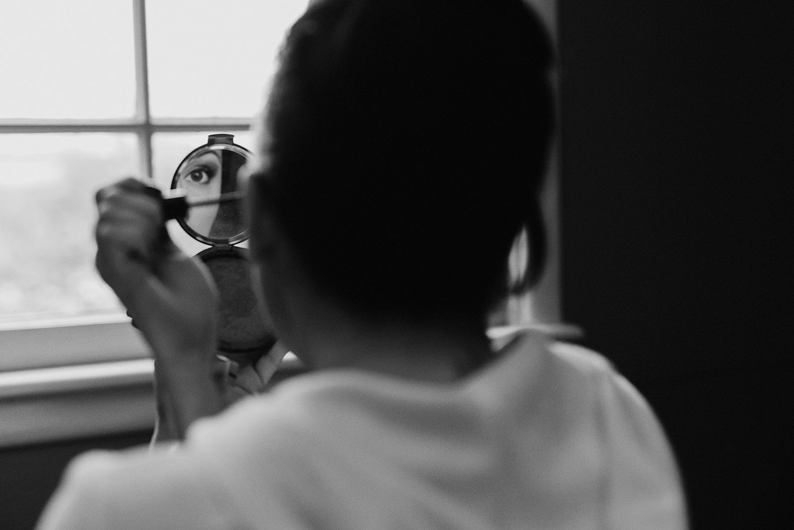 Bride putting on makeup in a hand mirror at The Colony St Johns Wedding