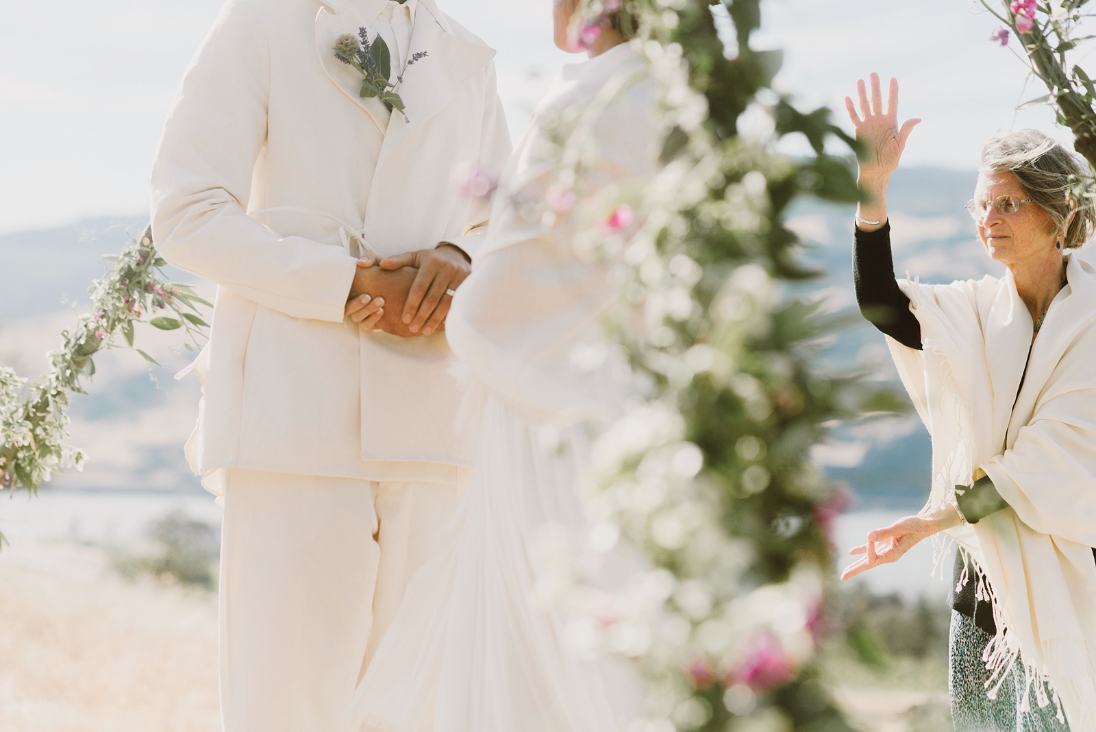 Bride and Groom holding hands while being blessed by a spiritual officiant - Columbia Gorge River Wedding in Oregon