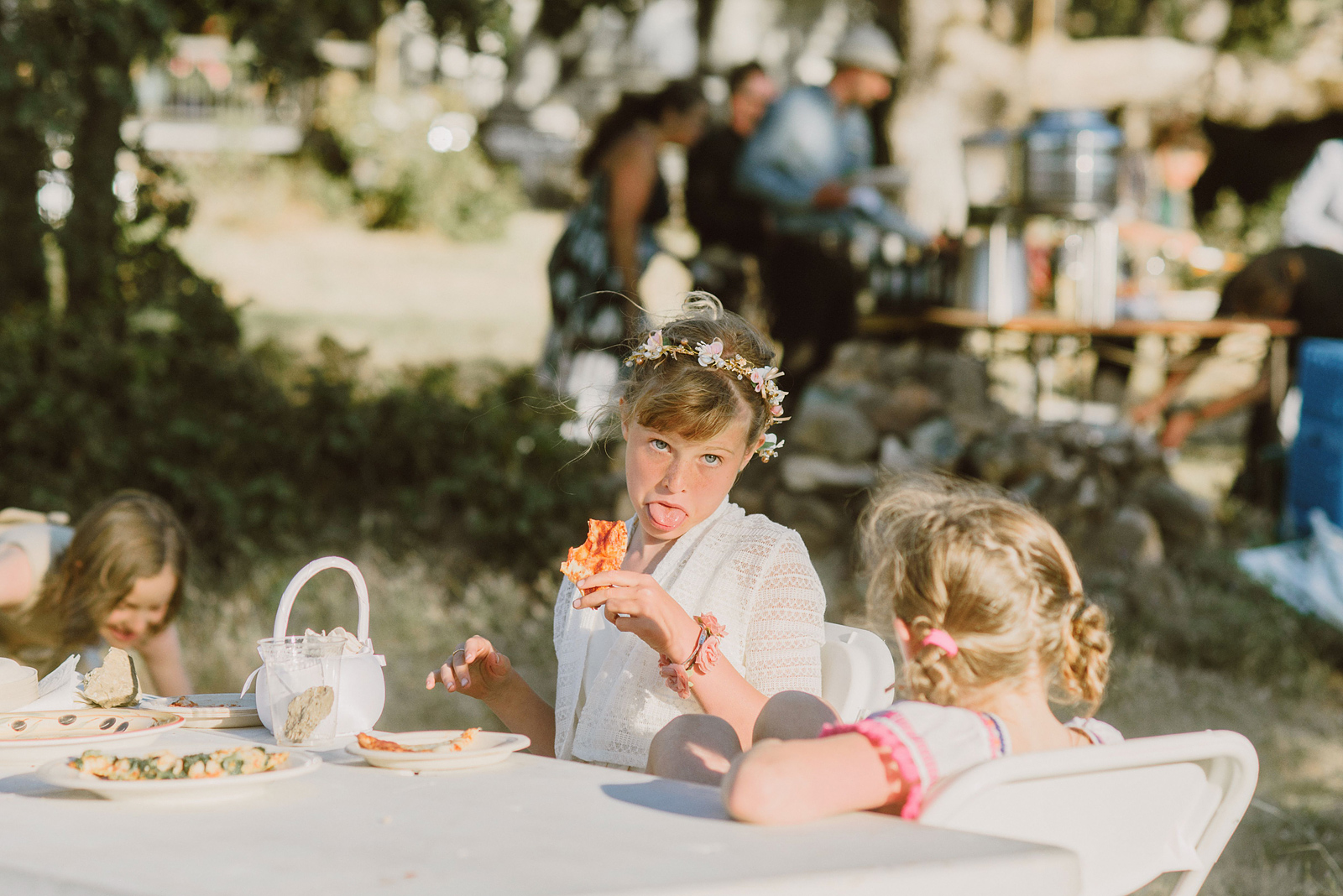 Flower girl sticking her tongue out while eating pizza at the kid's table - Columbia River Gorge wedding reception in Mosier, OR