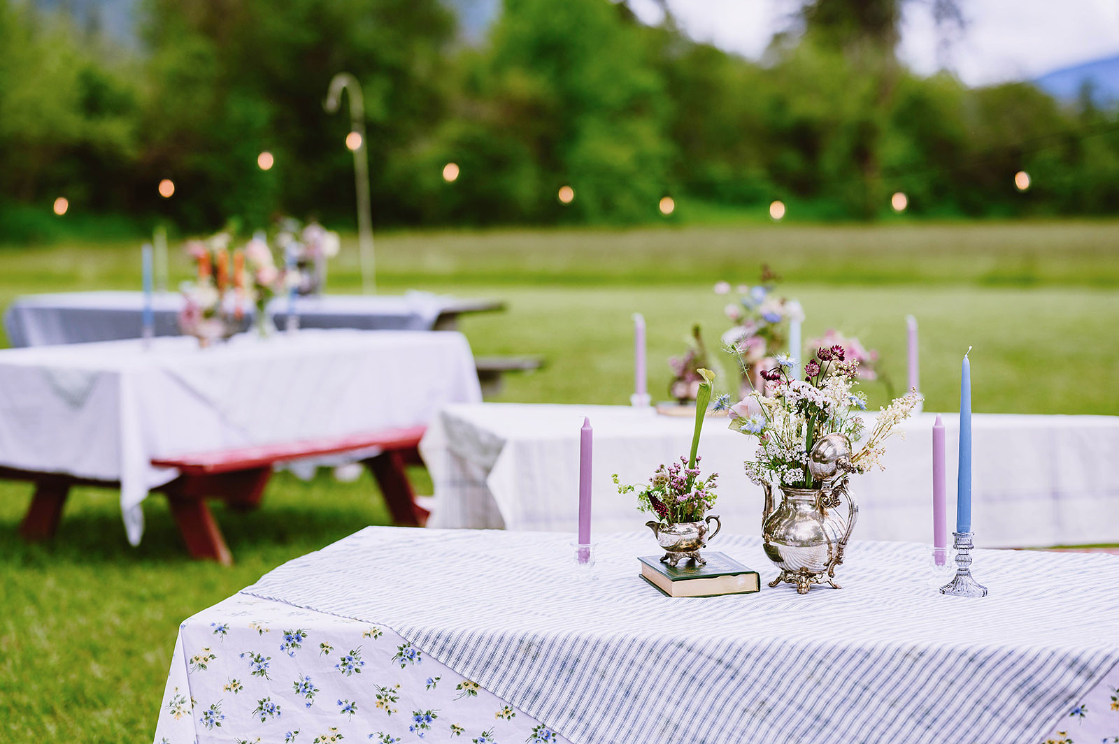Picnic tables at Hollenbeck Park set with candles and flowers in teapot vases for a Trout Lake Wedding