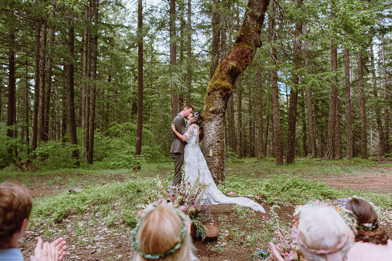 Bride and Groom kiss at the base of a tree in a forest clearing - Trout Lake Wedding, WA