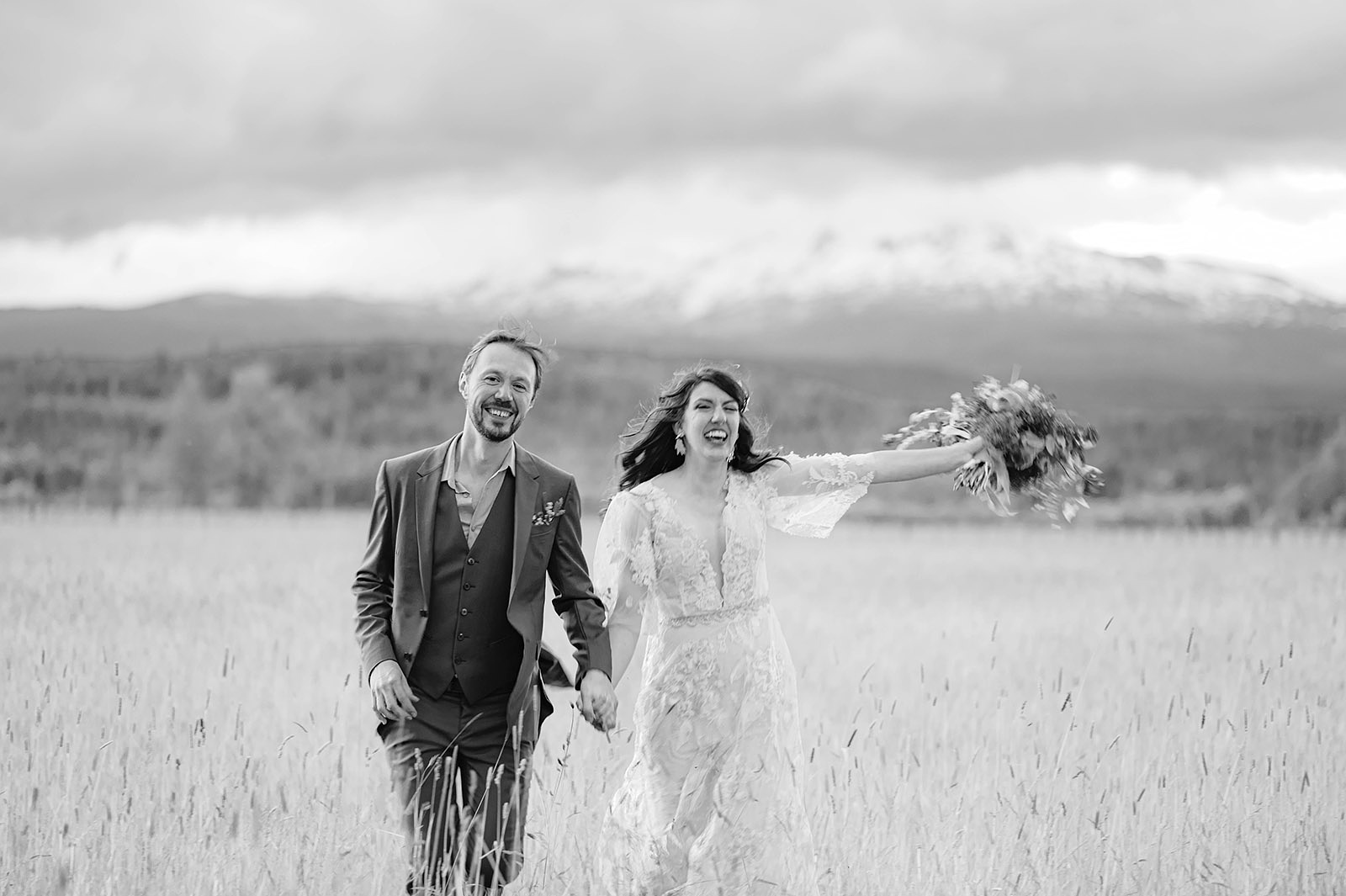 Bride and groom running towards the camera in a field of tall grass - Trout Lake Wedding, WA