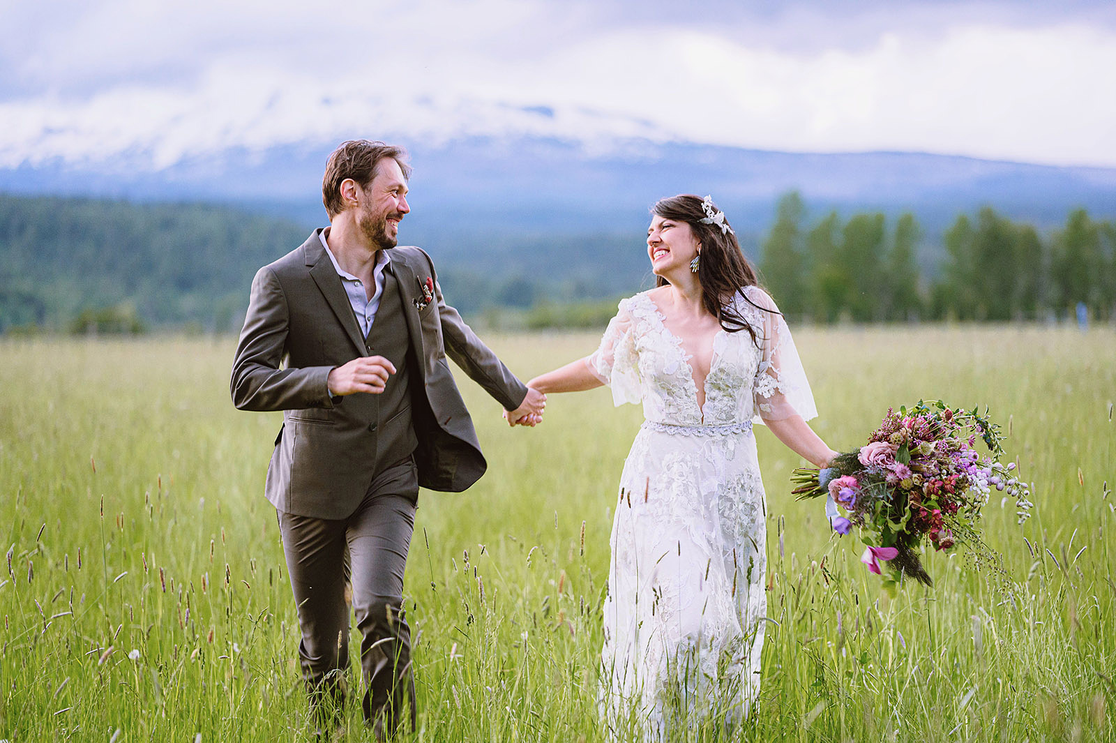 Bride and Groom smiling while holding hands and running through a field of tall grass at Hollenbeck Park - Trout Lake Wedding, WA