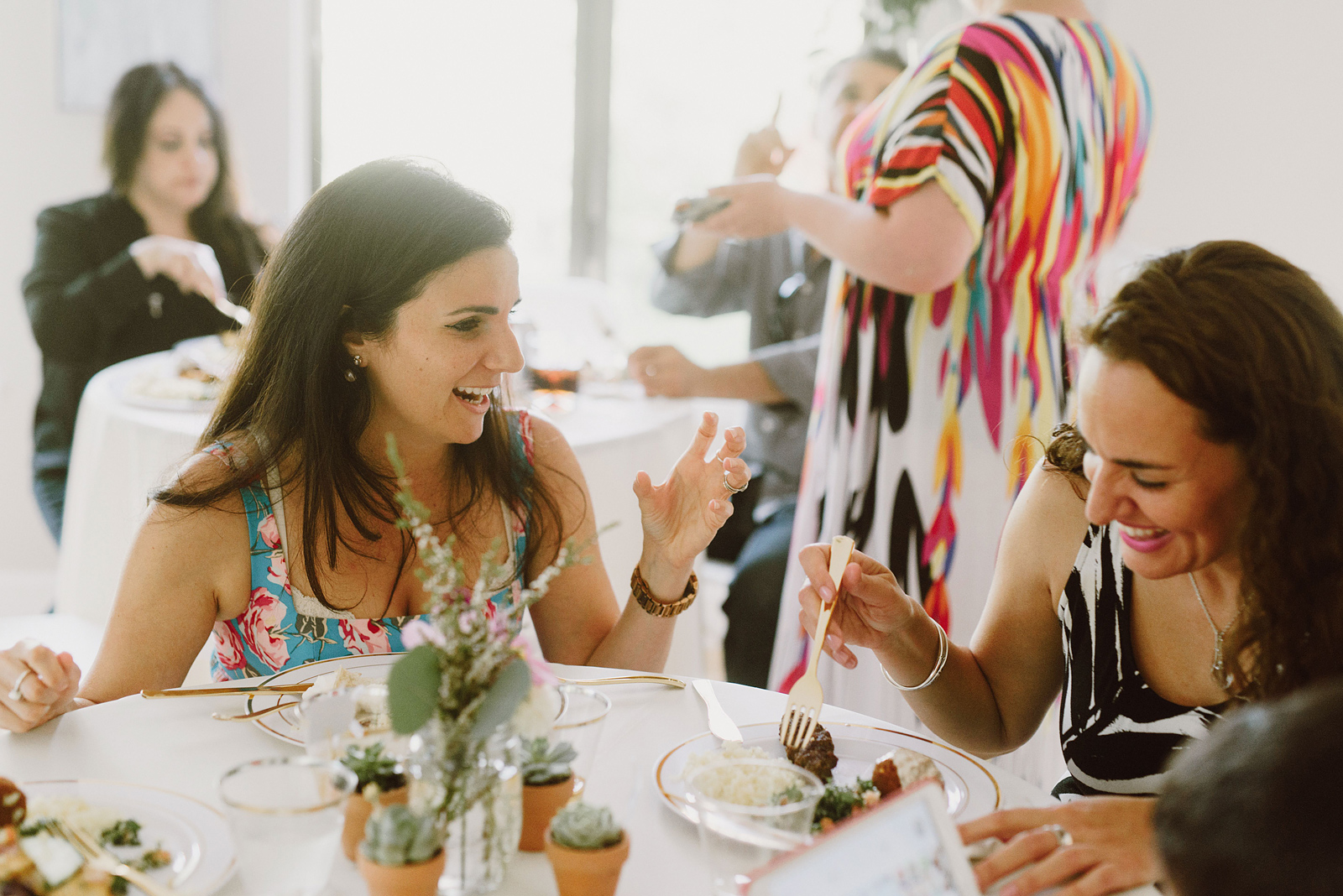 Candid photo of wedding guests talking and laughing at their dinner table - Oaks Pioneer Church Wedding