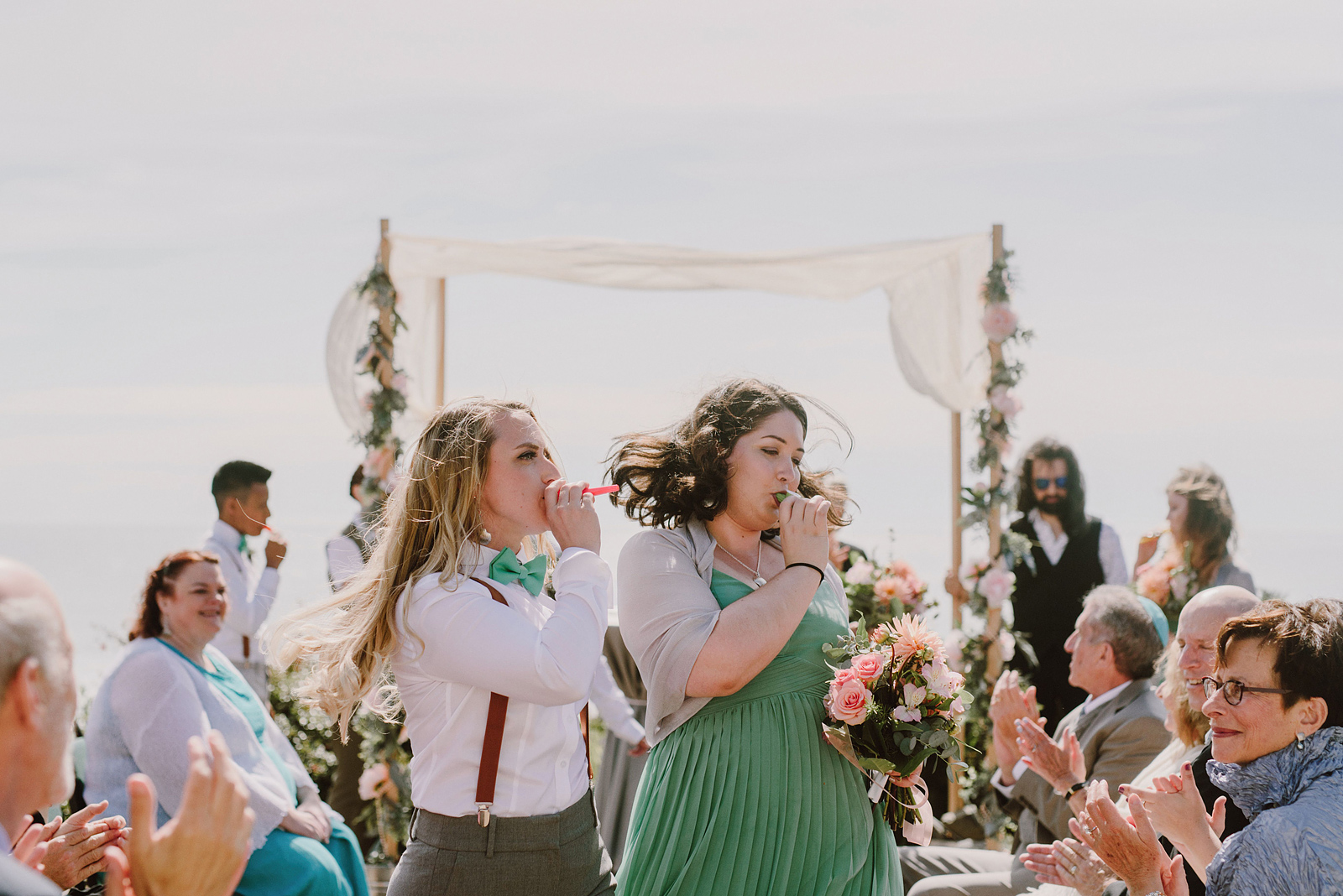 Wedding party playing kazoos during the ceremony recessional - Oceanside Community Club Wedding on the Oregon Coast” title=