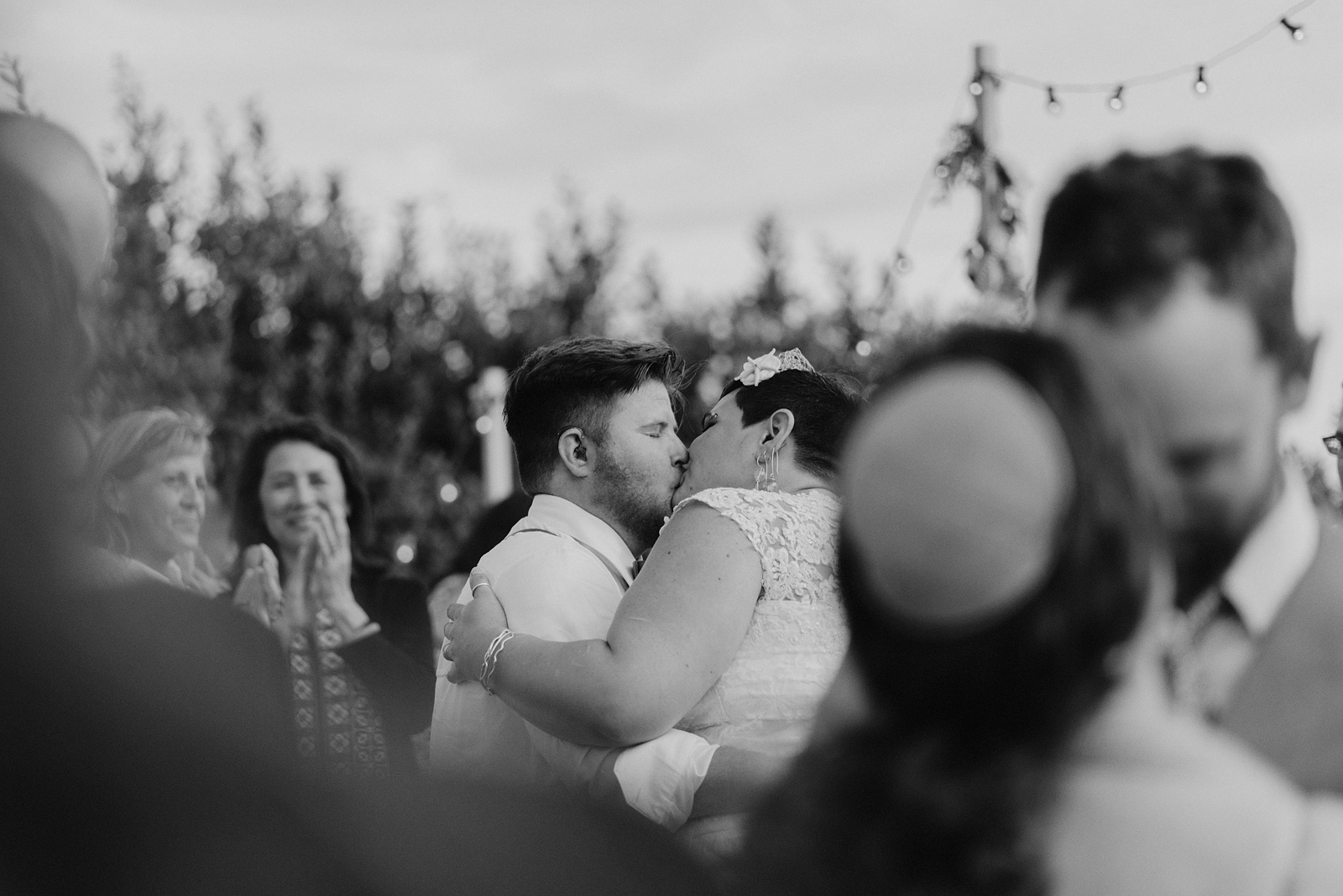 Black and white photo of bride and groom kissing at the end of their first dance - Oceanside Community Club Wedding on the Oregon Coast” title=
